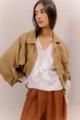 Campera liviana de lino color tostado, con cierre frontal de botones, bolsillos ojal en el pecho y mangas anchas con presilla y botón en los puños.