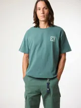 Remera de algodón orgánico color verde, de corte regular, con cuello redondo, mangas cortas y pequeño estampado gráfico en el pecho.