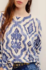 Sweater de punto color crudo con estampado geométrico en tonos azules, cuello redondo y mangas largas.