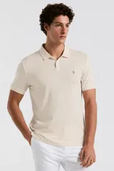 Remera polo de manga corta color beige, con cuello clásico y cierre frontal de botones. Cuenta con el logotipo bordado del pingüino en el pecho.
