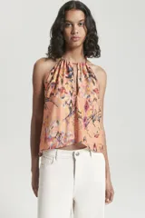 Top sin mangas con escote halter y abertura frontal. Presenta un diseño estampado multicolor, con ruedo irregular y detalle de bretel ajustable en el cuello.
