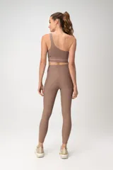 Top deportivo color beige, de un solo hombro, con banda inferior de mesh transparente.
