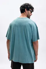 Remera de manga corta, corte oversize, con efecto lavado en tono verde azulado y estampa frontal con la palabra "Culture" en relieve o tono similar.