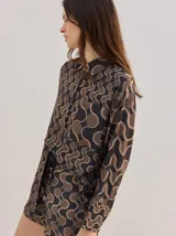 Camisa de algodón con estampado geométrico de ondas en tonos marrón y negro, corte holgado, mangas largas y cuello clásico.