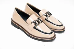 Mocasines de cuero vacuno en color arena, con ribete y detalle de cadena eslabonada en negro sobre el empeine. Poseen suela baja y tacón sutil.