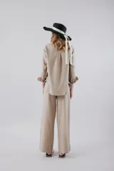 Pantalón de vestir color beige, de corte recto y tiro alto, con bolsillos laterales y cierre frontal con botón y cremallera.