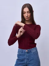 Top de punto ajustado al cuerpo, color bordó, con cuello redondo y mangas largas. Presenta un diseño acanalado vertical con costuras decorativas que forman una silueta en el frente.