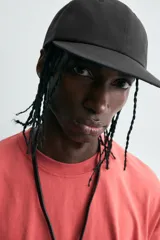 Gorra de seis paneles color negro, confeccionada en tejido técnico, con visor plano y ajuste trasero.