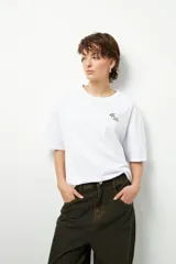 Remera negra de corte oversize con cuello redondo y manga corta. Presenta un pequeño estampado dorado en el pecho con la frase "love earth" y un símbolo de hojas.