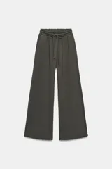 Pantalón de tiro medio con pierna ancha, confeccionado en tejido lavado. Presenta cintura elástica ajustable con cordones, bolsillos laterales y bolsillos traseros decorados con estrellas y aplicaciones de tachas. El diseño cuenta con terminaciones desflecadas en el ruedo.