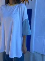 Remera de corte oversize confeccionada en tejido de punto acanalado color celeste, con mangas cortas en color amarillo y detalle de parche bordado con la bandera de Uruguay en la parte superior de la espalda.