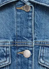 Chaqueta de jean estilo crop, confeccionada en algodón con un toque de elastano, de diseño recto y color azul. Presenta cuello camisero, cierre frontal con botones metálicos, mangas largas con puños abotonados y dos bolsillos de parche con solapa en el pecho.