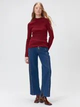 Remera de cuello alto tipo polera, confeccionada en tela rib con textura acanalada y ajuste al cuerpo. Presenta mangas largas y un pequeño bordado distintivo en la parte inferior.