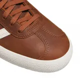 Championes Adidas modelo Gazelle ADV, color marrón con las icónicas tres tiras laterales en blanco y suela de goma blanca. Presentan un diseño clásico de perfil bajo con cierre de cordones.