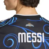 Camiseta de fútbol Adidas de la Selección Argentina, edición especial con diseño gráfico de hojas en tonos azules sobre fondo negro. Presenta el número 10 en el frente, el logo de Adidas, el parche de campeón del mundo FIFA 2022 y el escudo de la AFA.