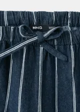 Pantalón de corte recto y tiro regular, confeccionado en algodón con diseño de rayas verticales. Presenta cintura elástica con cordón ajustable y bolsillos laterales.