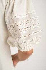 Remera negra de algodón con mangas tres cuartos abullonadas y detalle de bordado calado tipo ojal en la zona del antebrazo.