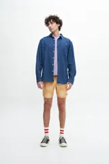 Camisa de denim celeste, manga larga, confeccionada en tela 100% algodón. Tiene un bolsillo en el pecho y botones personalizados.