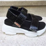 Sandalias con plataforma color negro, con tiras anchas con textura croco y hebillas plateadas.