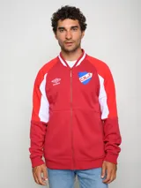 Campera tipo bomber de felpa, color rojo con detalles en blanco en las mangas y cuello. Presenta cierre frontal completo, logo de Umbro y escudo del Club Nacional de Football bordados en el pecho.
