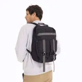 Mochila urbana Merrell modelo Gundahoo Urban Back, confeccionada en lona de poliéster color negro. Presenta un diseño funcional con correas de ajuste grises en el frente con hebillas de liberación rápida, compartimento principal con cierre de doble cursor y logo de la marca en la parte superior.