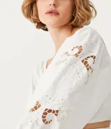 Blusa corta blanca de algodón con escote cuadrado, manga larga abullonada con bordados, y látex en la espalda.