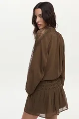Blusa verde oliva vaporosa con mangas abullonadas y encaje transparente, con bordado floral artesanal y detalles de canutillos.