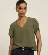 Blusa de manga corta con escote en pico, confeccionada en tejido de poliéster con textura tipo airflow. Presenta un diseño de mangas tulipán cruzadas y corte recto.