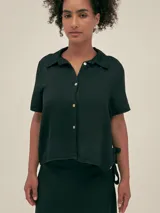Camisa negra de manga corta con cuello camisero y botones nacarados. Confeccionada en tejido lino-tencel y detalle de Polonio en cobre.