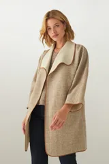 Tapado de largo medio abierto con cuello, confeccionado en lana fina sin teñir con detalles de terminación envivados en los bordes y mangas tres cuartos.