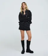 Campera overshirt de jean negro con cuello polo, cierre frontal abotonado, mangas largas y bolsillos delanteros decorados con tachuelas metálicas.