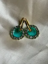 Aros de acero quirúrgico con dije circular de resina rosa y borde de strass dorados.