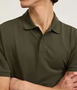 Remera polo de manga corta color verde militar, confeccionada en algodón peruano con cuello convencional y cierre de botones.