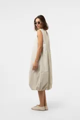 Vestido midi de silueta amplia y relajada, sin mangas, con escote redondo y costuras decorativas. Presenta una falda con corte y volumen.