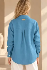 Camisa de lino color mostaza, de corte clásico con cuello camisero, manga larga y cierre frontal abotonado.