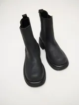 Bota tipo chelsea de cuero vacuno en color rojo con estampado floral grabado en negro. Presenta paneles laterales elásticos, suela de plataforma y taco cuadrado en color negro.