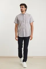 Camisa azul de manga corta, con cuello abotonado y bolsillo en el pecho.