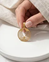 Dije circular de acero con baño de oro, con diseño calado de líneas curvas y geométricas.
