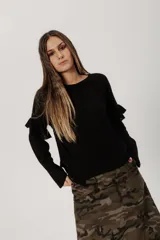 Buzo negro de punto con lanilla tipo canelon, corte flojo, mangas caídas y aberturas laterales.