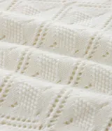 Camisa polo blanca de manga corta con cuello y tejido de punto con textura calada en forma de rombos.