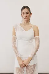 Vestido largo blanco de encaje con diseño asimétrico, tirante fino en un hombro y falda transparente.