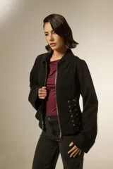 Sobrecamisa de jean color negro con cierre frontal, cuello clásico y detalle de cordones laterales ajustables con ojalillos metálicos.