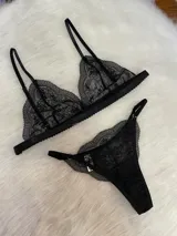 Conjunto de lencería de tres piezas en encaje negro. Incluye bralette con breteles regulables, collarín integrado con cuello ajustable y tanga regulable con corte media less.