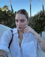 Collar artesanal con dije central de metal con textura orgánica irregular que evoca una ostra. El dije está montado sobre un cordón de algodón natural, permitiendo un uso versátil y regulable.