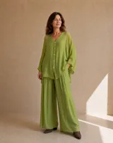 Camisa holgada de seda en color verde lima, con cuello en V, mangas largas amplias y cierre frontal de botones claros.