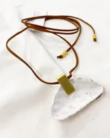 Collar con dije de nácar irregular, engarzado con pieza rectangular de metal dorado. El collar es de cuero marrón con cuentas doradas en los extremos.