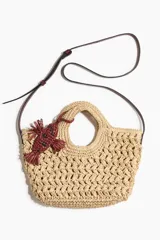 Cartera cruzada de paja trenzada de papel con doble asa, cierre magnético y correa bandolera ajustable. Incluye dije decorativo en forma de pez bordado en color bordó.
