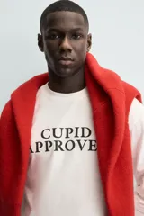 Camiseta de manga larga color blanco roto, corte relajado (relaxed fit) con cuello redondo y texto estampado en negro en el pecho que dice "CUPID APPROVED".