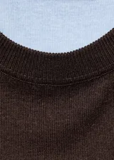Jersey de punto fino con cuello redondo y diseño combinado. Presenta un cuerpo en color marrón oscuro con paneles laterales y mangas en color celeste claro.