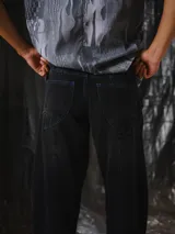 Pantalón de jean negro de corte amplio, inspirado en las bombachas de campo, con costuras a contratono en color azul y bolsillos Temblad.